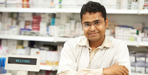 Male pharmacist with his arms folded smiling towards the camera